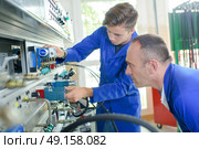 Apprentice electrician under supervision. Стоковое фото, агентство Ingram Publishing / Фотобанк Лори