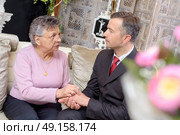 Suited man holding hands of elderly lady. Стоковое фото, агентство Ingram Publishing / Фотобанк Лори