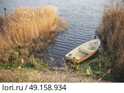 Yellow fishing boat in a dark lake in the autumn season surrounded by colorful reeds in the water. Стоковое фото, агентство Ingram Publishing / Фотобанк Лори