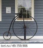 Penny farthing bicycle against house on sidewalk, Sherbrooke, Nova Scotia, Canada. Стоковое фото, агентство Ingram Publishing / Фотобанк Лори