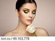 Portrait of beautiful young woman with rainbow make-up. Girl summer. Long eyelashes, vivid colorful eyeshadows. White rose. Multicolored. Стоковое фото, агентство Ingram Publishing / Фотобанк Лори