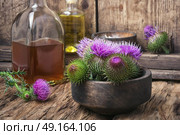 Beautiful blossoming buds thistle. Wild plant thistle also medicinal tincture on a wooden surface. Стоковое фото, агентство Ingram Publishing / Фотобанк Лори