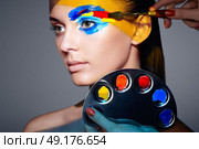 Makeup artist applies colorful makeup. Fashion model woman with colored face painted. Beauty art portrait of beautiful model with colorful abstract makeup. Стоковое фото, агентство Ingram Publishing / Фотобанк Лори