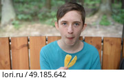 12-летний мальчик ест чипсы в парке. Стоковое видео, видеограф Яна Проничева / Фотобанк Лори