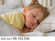 Peaceful adorable baby sleeping on a bed at home. Slumbering little child. Two years old girl sleeps peaceful at domestic room interior background. Serene dream. Cute face close up. Deep kid slumber. Стоковое фото, фотограф Марина Демидюк / Фотобанк Лори