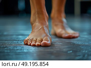 Close-up of bare feet stepping on a wooden floor in a dimly lit room during a wellness activity. Стоковое AI-изображение, AI-художник Климов Денис / Фотобанк Лори