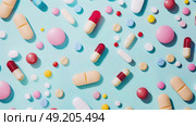 Assorted pills in different colors spread out on a blue table. Стоковое AI-изображение, AI-художник Данила Большаков / Фотобанк Лори