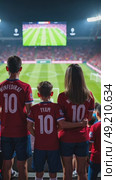 A portrait of a family at a fan zone, parents and children all wearing matching jerseys, their faces lit by the glow of a giant screen showing a sport game. Стоковое AI-видео, аниматор Sergey Grishin / Фотобанк Лори