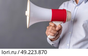 A man holding a red and white megaphone, preparing to speak through the device. Стоковое AI-изображение, AI-художник Данила Большаков / Фотобанк Лори