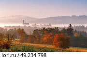 Tower of rural church in misty autumn morning. Autumn colorful morning with fog and sun rising over a mountain village. Sunrise Poland scene. Стоковое фото, агентство Ingram Publishing / Фотобанк Лори