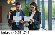 Business colleagues reviewing documents in modern office lobby, geometric lighting fixtures casting interesting shadows. Стоковое AI-видео, аниматор Sergey Grishin / Фотобанк Лори