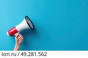 A person is holding a megaphone and pointing it at a blue wall. Стоковое AI-изображение, AI-художник Ярославский Максим / Фотобанк Лори