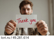 A man holding a white card that says "Thank You" in red. Стоковое AI-изображение, AI-художник Ярославский Максим / Фотобанк Лори