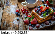 French toast topped with fresh berries and powdered sugar on a decorative plate, served with a cup of coffee. Close-up food photography. Gourmet breakfast and brunch concept. Стоковое AI-изображение, AI-художник Konstantin Plotnikov / Фотобанк Лори