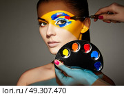 Makeup artist applies colorful makeup. Fashion model woman with colored face painted. Beauty art portrait of beautiful model with colorful abstract makeup. Стоковое фото, агентство Ingram Publishing / Фотобанк Лори