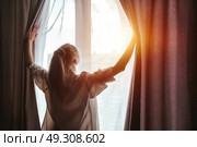 Chasing Sunshine Young Woman Opening Curtains at Home in the Morning. Стоковое фото, фотограф Aleksandr Golubev / Фотобанк Лори