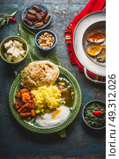 Assorted indian food. Bowls with paneer cheese , curries, rice, naan bread, samosas, chicken,chutney and spices on dark rustic background, top view. Стоковое фото, агентство Ingram Publishing / Фотобанк Лори