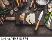 Sliced celery on wooden cutting board with knife on rustic kitchen table background with pot and others root vegetables ingredients for tasty cooking, top view. Healthy and clean food. Стоковое фото, агентство Ingram Publishing / Фотобанк Лори