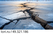 Cracked icy soil in extreme cold, showing layers of frozen earth and frost heaves. Life in permafrost conditions, climate change problems on the planet. Global warming. Стоковое AI-изображение, AI-художник ALLA YURTAYEVA / Фотобанк Лори