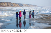 Children playing near a frozen lake in permafrost zone, bundled in colorful clothing. Life in permafrost conditions, climate change problems on the planet. Global warming. Стоковое AI-изображение, AI-художник ALLA YURTAYEVA / Фотобанк Лори