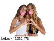 Best friends teen girls with bubble gum and heart fingers shape gesture. Стоковое фото, агентство Ingram Publishing / Фотобанк Лори