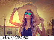 Blond teen girl sunglasses and pamela sun hat at palm tree sunset filtered image. Стоковое фото, агентство Ingram Publishing / Фотобанк Лори