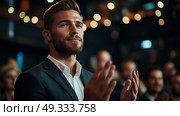 Focused young man applauding during an event in a crowded venue with warm lighting and a lively atmosphere. Стоковое AI-изображение, AI-художник Сергей Толмачёв / Фотобанк Лори