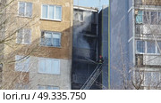 Firefighter climbing ladder and extinguishing fire on apartment balcony. Стоковое видео, видеограф Mikhail Davidovich / Фотобанк Лори