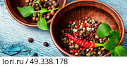 Different kinds of peppercorns.. Black,red and white pepper in clay bowl.Set of different peppers. Стоковое фото, агентство Ingram Publishing / Фотобанк Лори