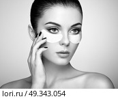 Portrait of Beauty Woman with eye Patches showing an effect of Perfect Skin. Beautiful Face of young Woman with clean Fresh Skin and bare shoulders on beige background. Brunette Spa Girl. Стоковое фото, агентство Ingram Publishing / Фотобанк Лори