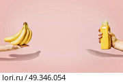 Summer food and beverages background with bananas and yellow drink bottle in female hand at pastel pink background, front view, banner or template. Стоковое фото, агентство Ingram Publishing / Фотобанк Лори