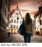 girl traveler stands with a backpack in the background of Tallinn. Old streets of European cities. Стоковое фото, агентство Ingram Publishing / Фотобанк Лори