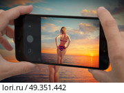 girl in a swimsuit standing near the sea at sunset. Photographing a blogger on a mobile phone. girl in a swimsuit standing near the sea at sunset. Стоковое фото, агентство Ingram Publishing / Фотобанк Лори