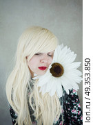 Happy blonde woman posing near a huge flower . Стоковое фото, агентство Ingram Publishing / Фотобанк Лори