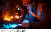 Miner carefully documenting findings while exploring a cave during nighttime with artificial lighting. Стоковое AI-изображение, AI-художник Сергей Толмачёв / Фотобанк Лори