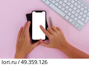 WARSAW, POLAND - DECEMBER 02, 2017: Two hands holding and touching New Iphone X mobile phone with cup of colorful apps icons. New Iphone X. New Iphone X. Редакционное фото, агентство Ingram Publishing / Фотобанк Лори