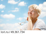 The elderly woman smiles and holds in hands glasses on a background of the blue sky. Grandmothers leisure. Стоковое фото, агентство Ingram Publishing / Фотобанк Лори