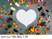 Colorful halloween candies on stone. Trick and treat - colorful halloween candies flat lay scene on stone with copy space on white heart. Стоковое фото, агентство Ingram Publishing / Фотобанк Лори