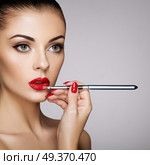 Beautiful Woman paints Lips with Lipstick. Beautiful Woman Face. Makeup detail. Beauty Model with Perfect Skin. Red Lips and Nails Manicure. Стоковое фото, агентство Ingram Publishing / Фотобанк Лори