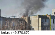 Black smoke rising from damaged roof of residential building after russian shelling. Стоковое видео, видеограф Mikhail Davidovich / Фотобанк Лори
