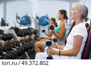 Mature sportswoman doing exercises with a barbell and dumbbells in gym. Стоковое фото, фотограф Яков Филимонов / Фотобанк Лори