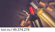 Bottles of red and white wine with corks on wooden tablet, toned image. Glass of red wine. Стоковое фото, агентство Ingram Publishing / Фотобанк Лори