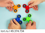 trendy fidget spinners - styled flat lay scene with hands holding colorful generic design spinners. fidget spinner, popular relaxing toy, generic design. Стоковое фото, агентство Ingram Publishing / Фотобанк Лори