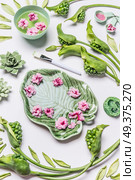 Spa or Wellness background. Bowl in shape of tropical leaf with flowers and water on white background with green leaves and calla flowers, top view. Beauty, relaxing and body care concept. Стоковое фото, агентство Ingram Publishing / Фотобанк Лори