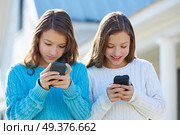 Sister twins having fun with technology mobile smartphone. Стоковое фото, агентство Ingram Publishing / Фотобанк Лори
