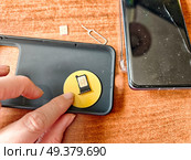 Customizing a phone case with a decorative sticker on a wooden table. Стоковое фото, фотограф Кривошеина Елена Леонидовна / Фотобанк Лори