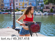 Girl riding a foldable e-bike in a Mediterranean port ebike. Стоковое фото, агентство Ingram Publishing / Фотобанк Лори