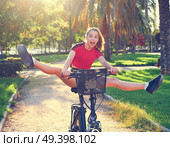 Acrobatic girl riding e-bike in a city park with red t-shirt foldable ebike. Стоковое фото, агентство Ingram Publishing / Фотобанк Лори