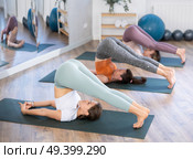 Sporty fit woman practicing hatha yoga doing inverted asana Halasana or Plough pose for stretching spine and back muscles in yoga studio. Стоковое фото, фотограф Яков Филимонов / Фотобанк Лори