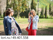 Two young tourist women taking photographs with analogic reflex camera in urban park. Travelers concept. Стоковое фото, агентство Ingram Publishing / Фотобанк Лори